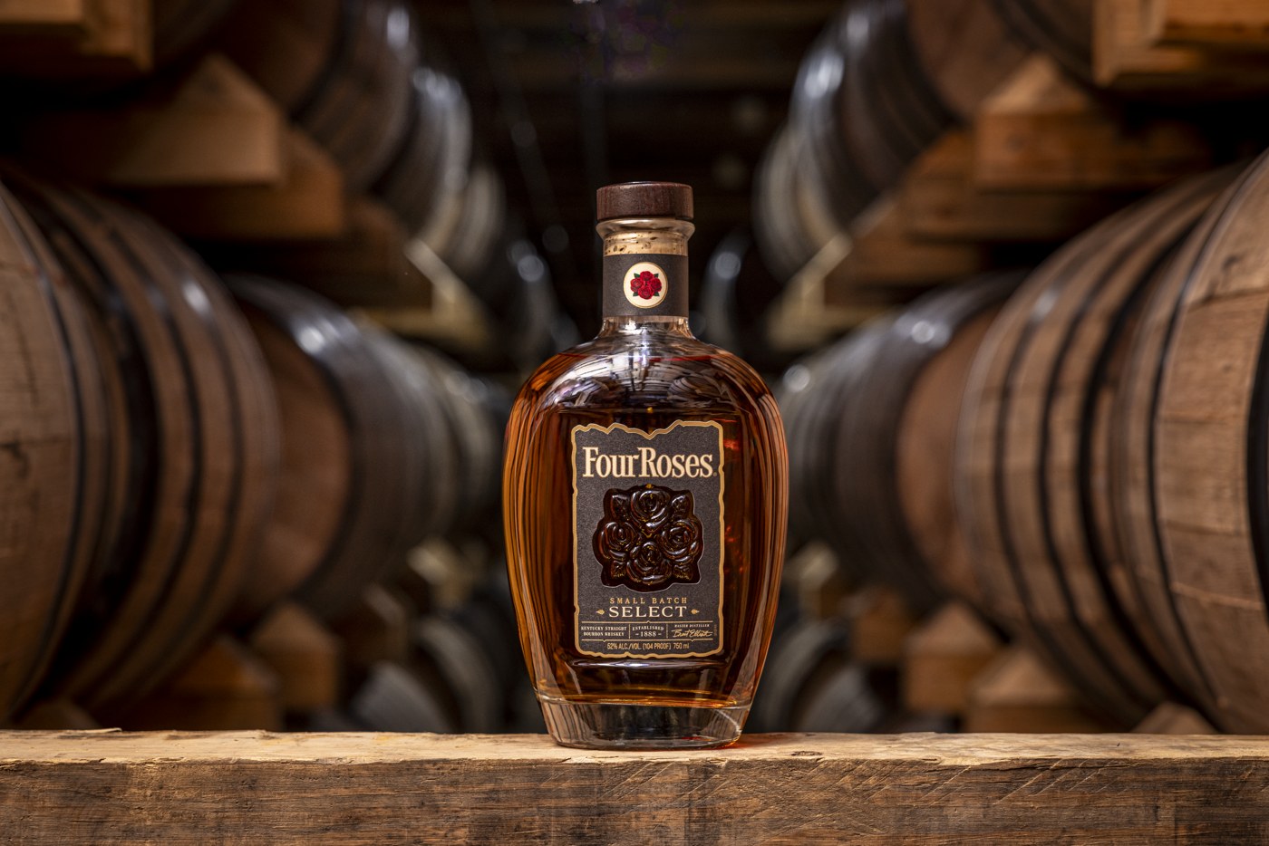 Four Roses Small Batch Select bottle among warehouse barrels